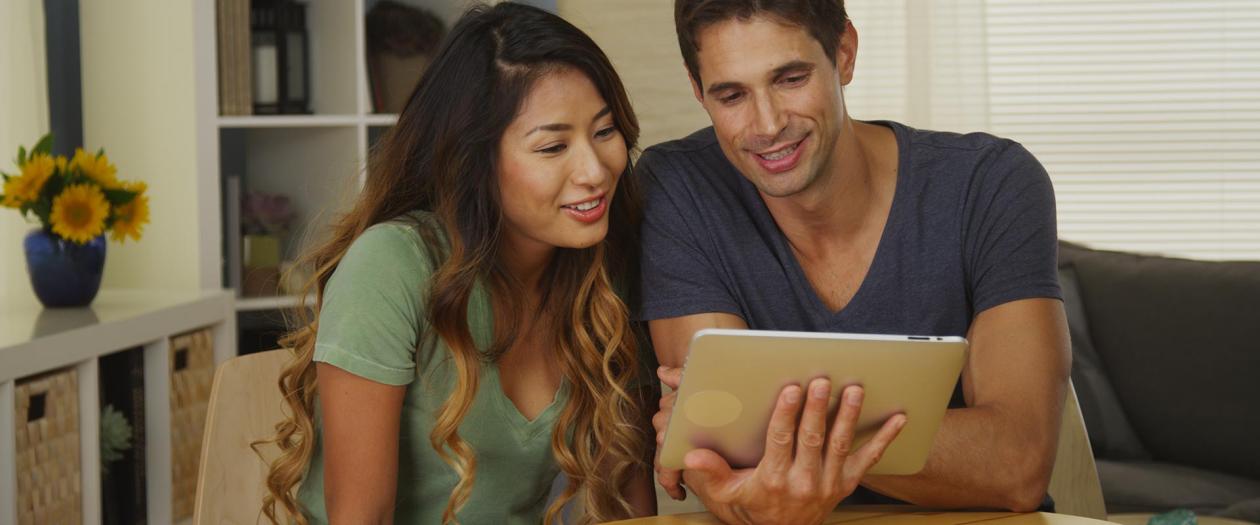 man and woman viewing tablet together